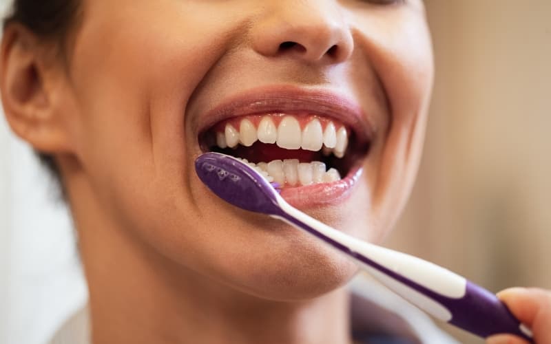 A woman brushing along her gum line with a toothbrush