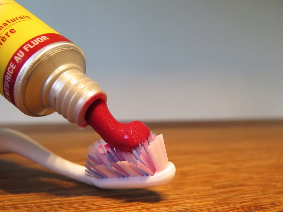 Fluoride toothpaste being squeezed onto a toothbrush