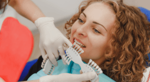 A shade guide held beside a patient's teeth during a veneer consultation