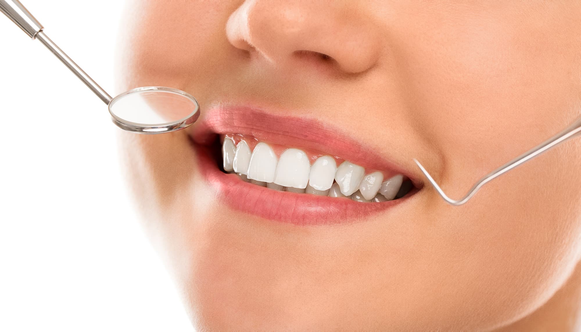 A dental mirror and probe held beside a patient's smile during an examination