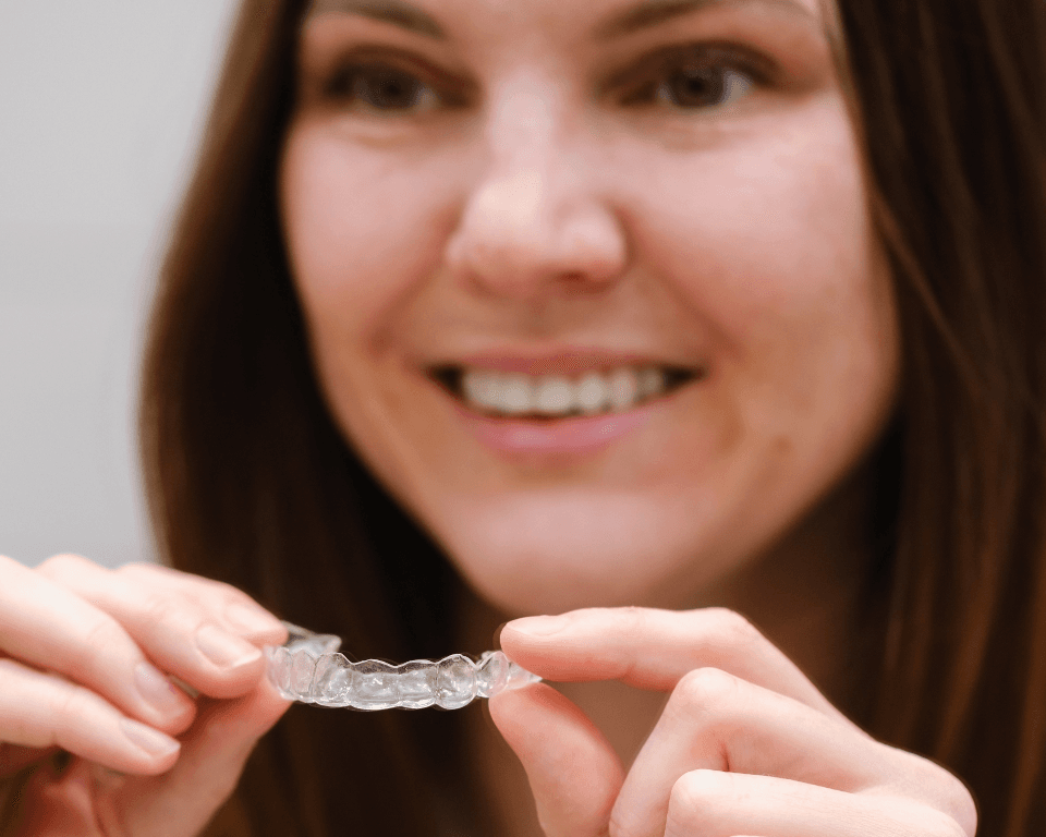 A patient holding a clear aligner up to the camera