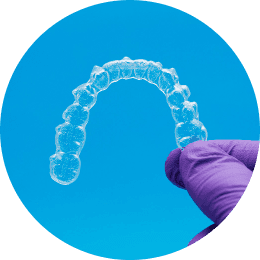 A gloved hand holding a clear orthodontic retainer